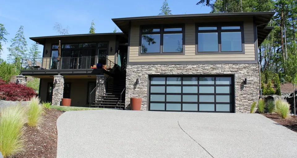 Double full-view garage door, 5 lites by 4, with a black frame and white laminated glass in a stacked stone lower story