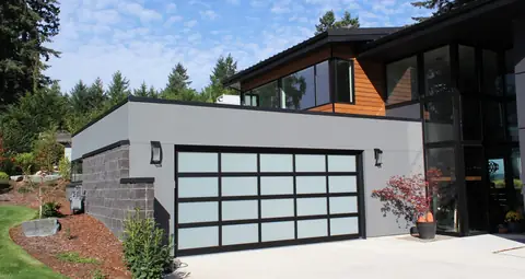 Double full-view garage door, 5 lites by 4, with a black frame and white laminated glass on a gray flat-roofed house