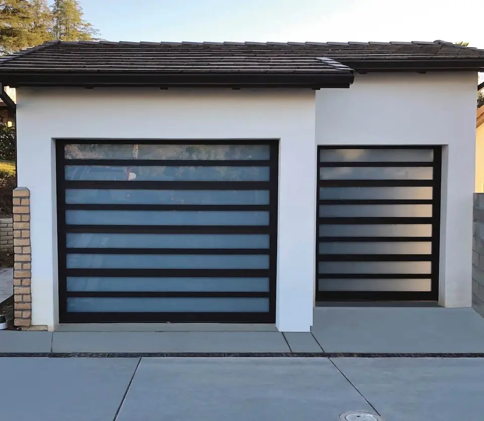 Two black-framed aluminum garage doors with narrow frosted glass rows, a double and a single, in a white stucco garage.
