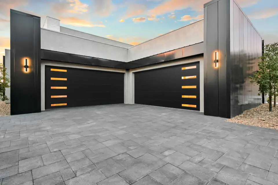 Two black flush steel double garage doors, each with five slim windows stacked at the outer edge, on a flat-roofed house