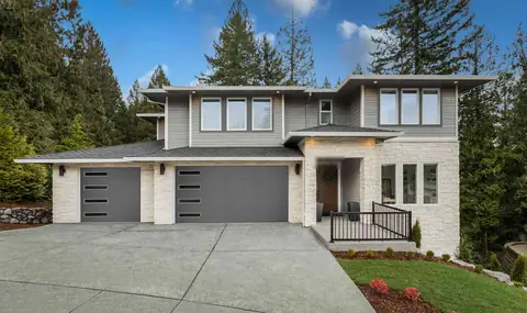 Charcoal flush steel garage doors, one single and one double, with four slim windows stacked at the left, on a gray two-story house