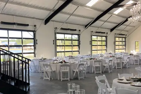 Four full-view glass sectional doors with black aluminum frames, closed along the wall of a white steel hall set with round tables.