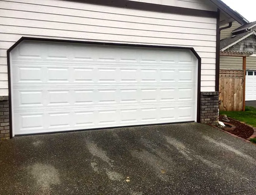 A double-width white raised-panel garage door in a clipped-corner opening