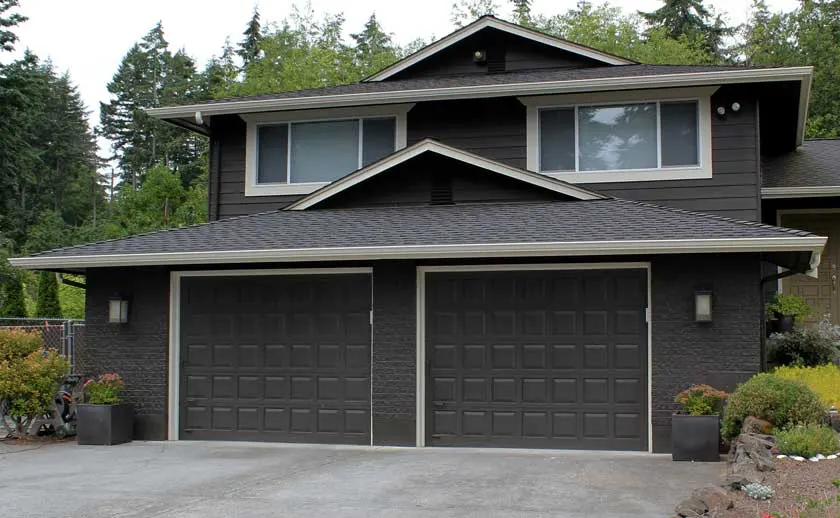 Before: two dark raised-panel doors on a dark two-story house