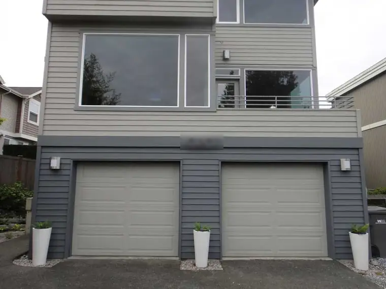 Before: two plain sectionals on a gray contemporary house with a lot of glass above them