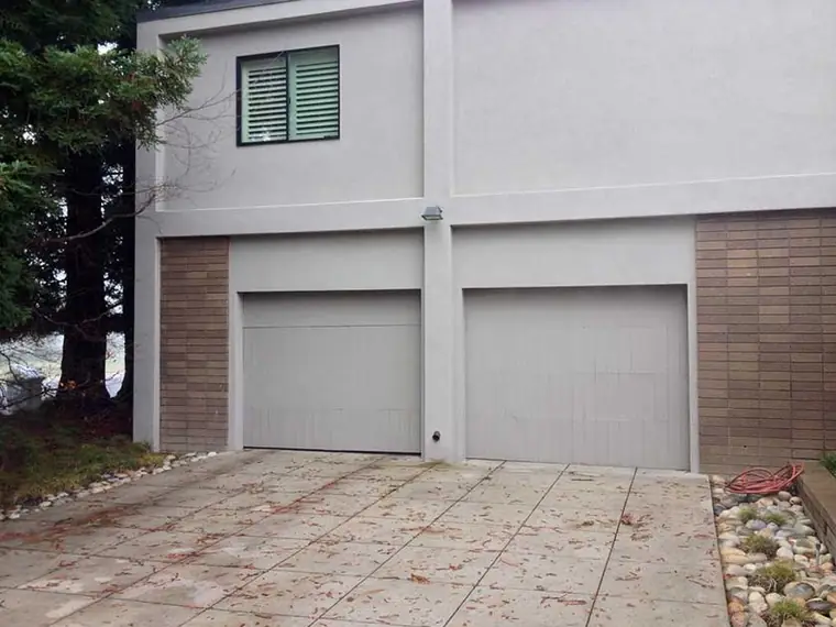 Before: two flush pale doors on a stucco house where the other openings are dark-framed glass